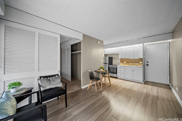 kitchen featuring a textured ceiling, wood-type flooring, white cabinetry, and stainless steel appliances