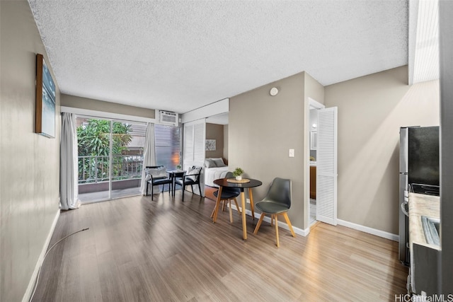 interior space featuring a wall mounted AC, a textured ceiling, and light wood-type flooring