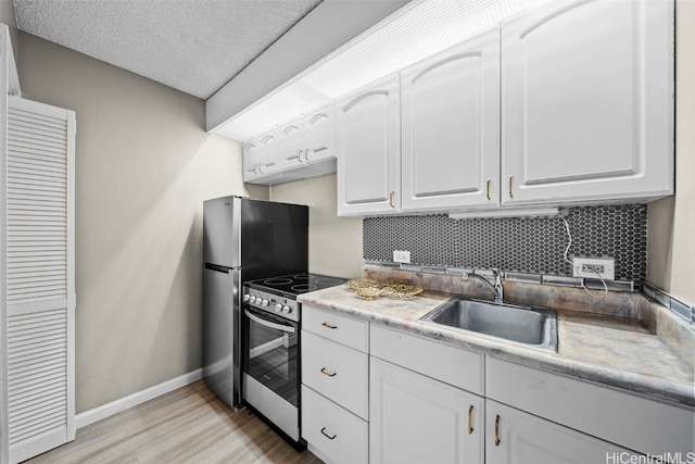 kitchen with appliances with stainless steel finishes, light wood-type flooring, a textured ceiling, sink, and white cabinetry