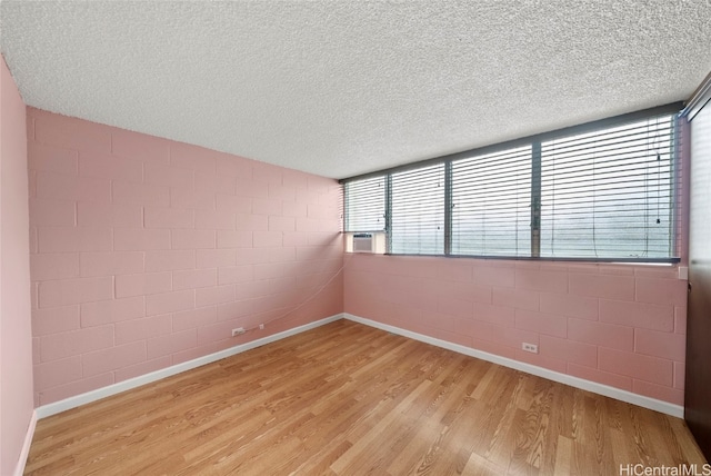 unfurnished room with plenty of natural light, light hardwood / wood-style floors, and a textured ceiling