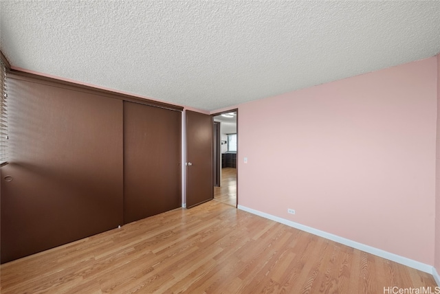 unfurnished bedroom featuring light wood-type flooring, a textured ceiling, and a closet