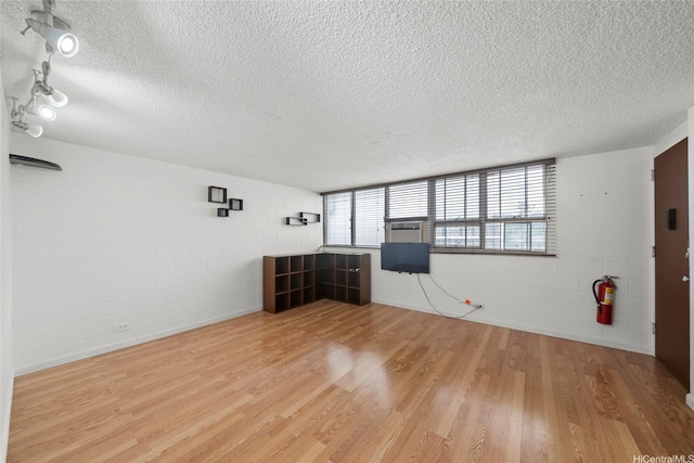 502 Captain Cook Ave Unit 303, Honolulu, HI 96813 - unfurnished living room with a textured ceiling, wood finished floors, concrete block wall, and cooling unit