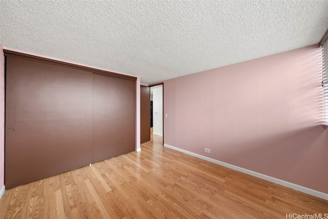 unfurnished bedroom with light hardwood / wood-style floors, a textured ceiling, and a closet