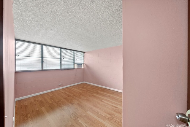 spare room with a textured ceiling and light wood-type flooring