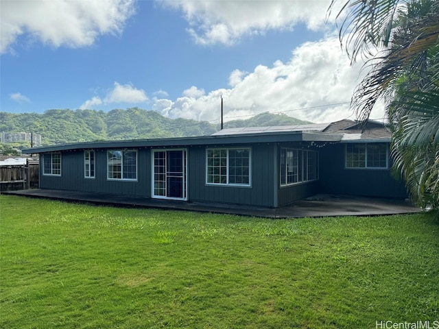 rear view of property featuring a lawn, a mountain view, and a patio