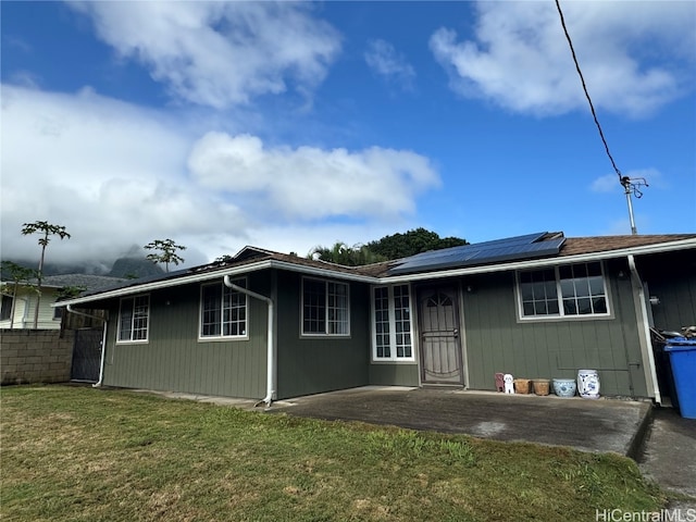 view of front facade featuring solar panels and a front lawn