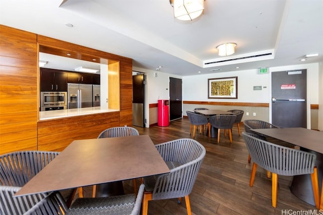 dining area with dark wood-type flooring and a tray ceiling