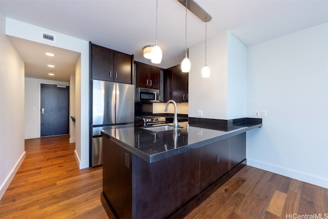 kitchen featuring sink, hanging light fixtures, kitchen peninsula, stainless steel appliances, and dark brown cabinets