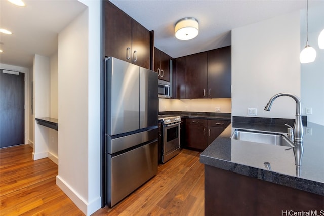 kitchen featuring dark brown cabinets, appliances with stainless steel finishes, sink, and hanging light fixtures