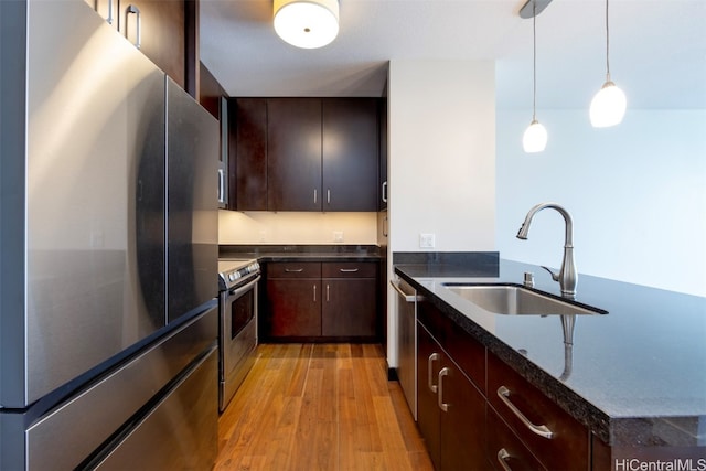 kitchen with dark brown cabinetry, sink, decorative light fixtures, light wood-type flooring, and stainless steel appliances