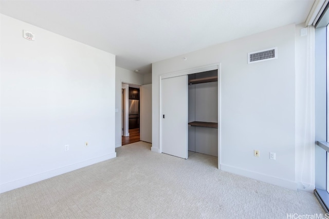 unfurnished bedroom featuring light carpet and a closet