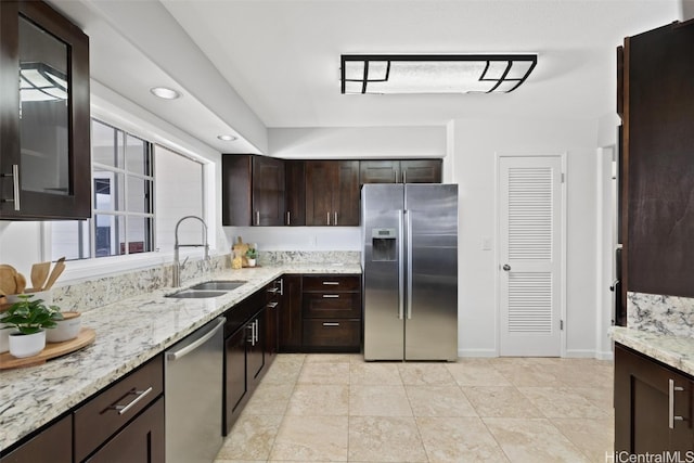 kitchen featuring dark brown cabinetry, appliances with stainless steel finishes, sink, and light stone countertops