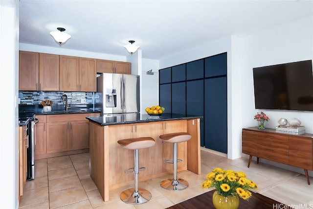 kitchen with light tile patterned flooring, stainless steel appliances, a kitchen island, backsplash, and sink