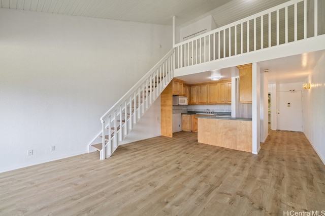 kitchen with a high ceiling, light wood-type flooring, and sink