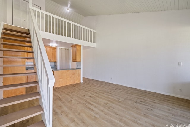 stairs with wood-type flooring and high vaulted ceiling