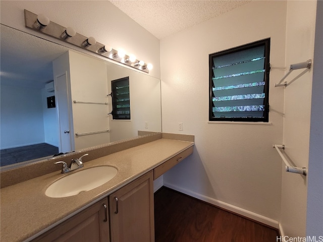 bathroom featuring baseboards, a textured ceiling, vanity, and wood finished floors