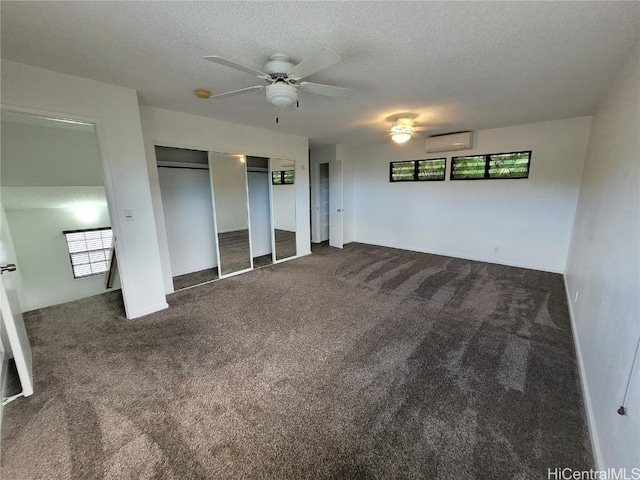 unfurnished bedroom with carpet, a textured ceiling, and a wall mounted air conditioner