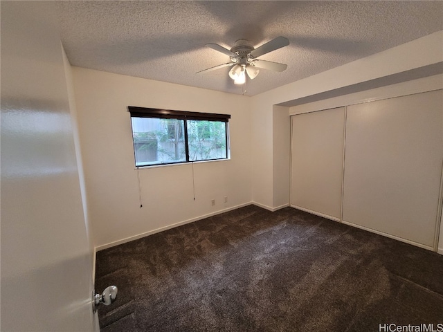 unfurnished bedroom featuring a ceiling fan, a closet, dark carpet, and a textured ceiling