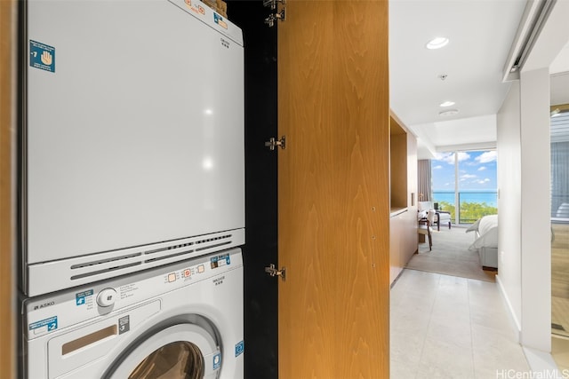 laundry area featuring water heater and stacked washer / drying machine