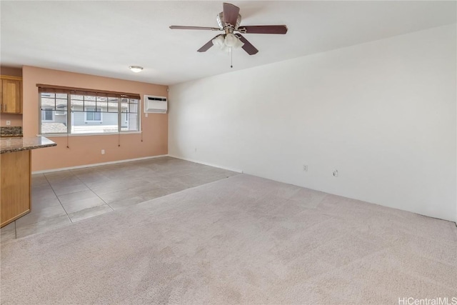 empty room featuring light tile patterned floors, a ceiling fan, an AC wall unit, and light colored carpet