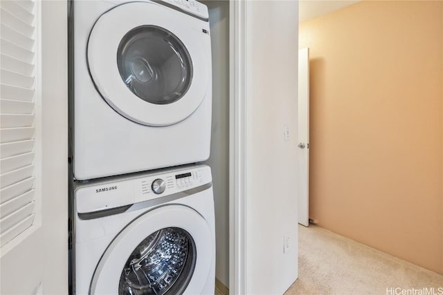 clothes washing area featuring stacked washer / drying machine, laundry area, and light carpet