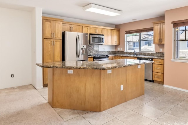 kitchen with plenty of natural light, appliances with stainless steel finishes, dark stone countertops, and a center island