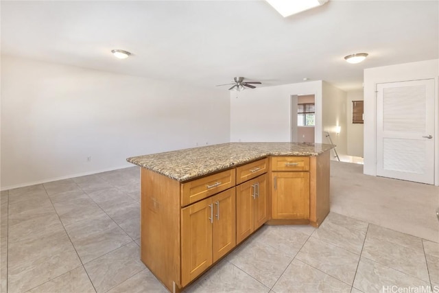 kitchen with a center island, open floor plan, brown cabinets, and light stone countertops