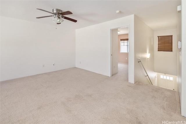 empty room featuring a ceiling fan and light colored carpet