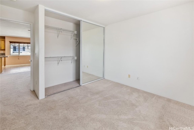 unfurnished bedroom featuring a closet and light colored carpet