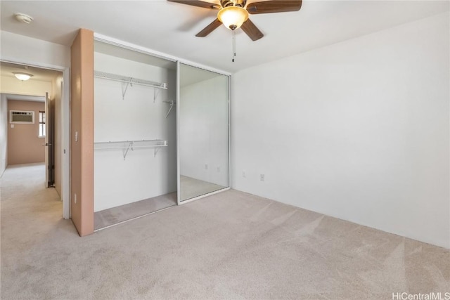 unfurnished bedroom with a closet, light colored carpet, ceiling fan, and a wall mounted AC