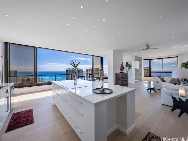 kitchen featuring white cabinets, expansive windows, a water view, light hardwood / wood-style flooring, and a kitchen island