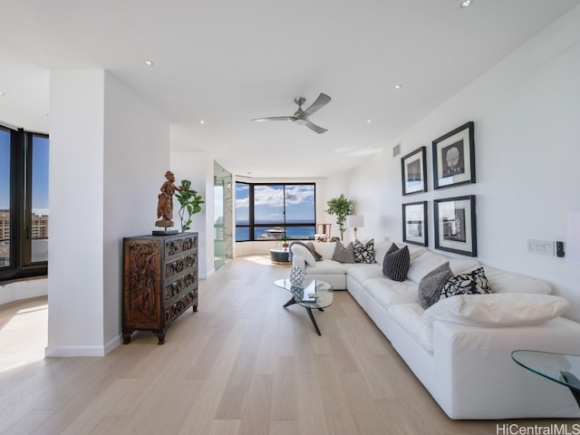 living room with light wood-type flooring, a wall of windows, and ceiling fan