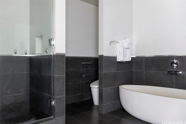 bathroom featuring walk in shower, tile patterned floors, toilet, and tile walls