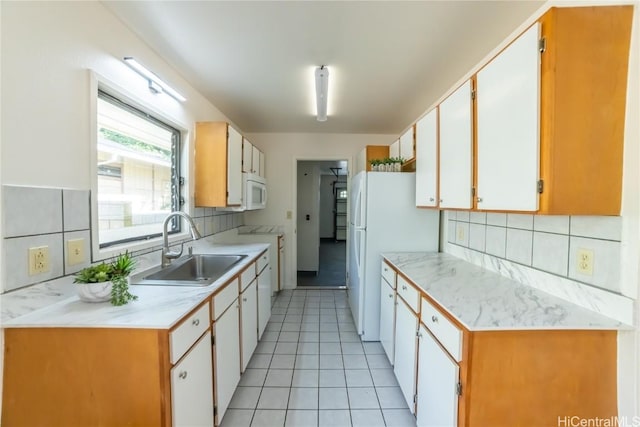 kitchen with decorative backsplash, white appliances, sink, white cabinets, and light tile patterned flooring