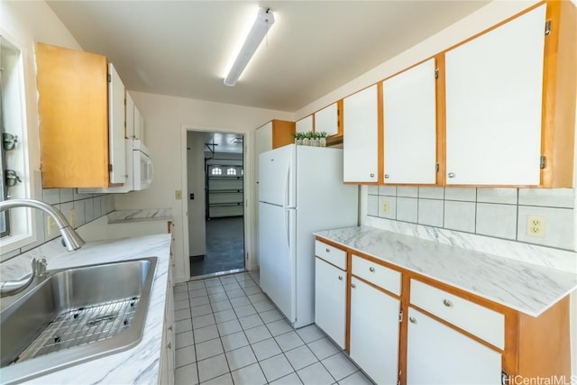 kitchen featuring sink, light tile patterned floors, backsplash, white appliances, and white cabinets