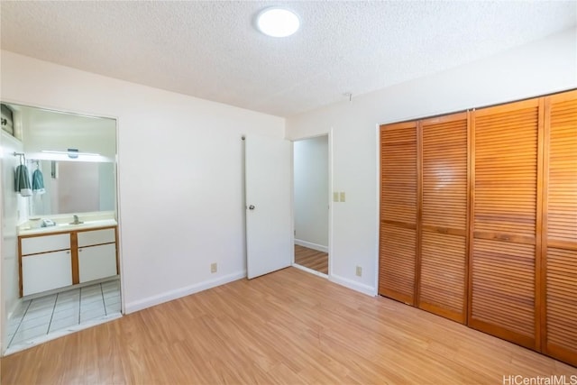 unfurnished bedroom with a closet, a textured ceiling, and light hardwood / wood-style flooring