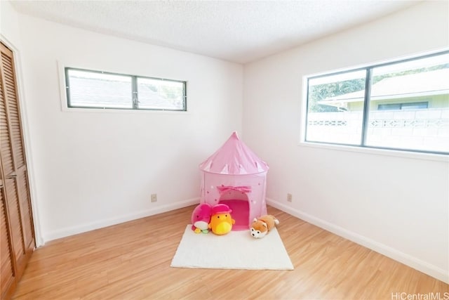 recreation room featuring light hardwood / wood-style floors and a textured ceiling