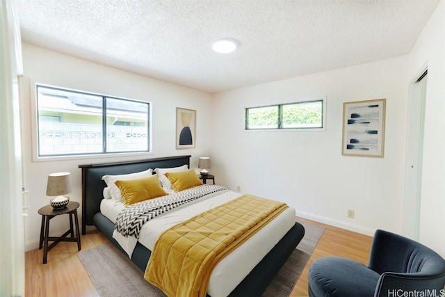 bedroom with multiple windows, a textured ceiling, and hardwood / wood-style flooring