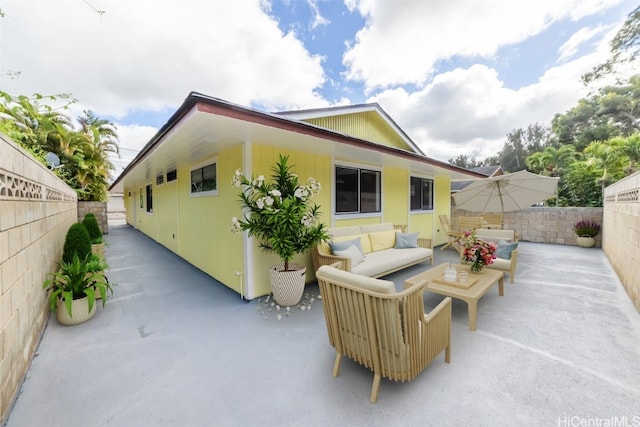 rear view of property with an outdoor living space and a patio