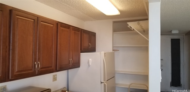 kitchen with white refrigerator and a textured ceiling