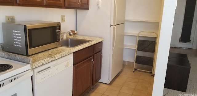 kitchen with light tile patterned floors, white appliances, light stone counters, and sink