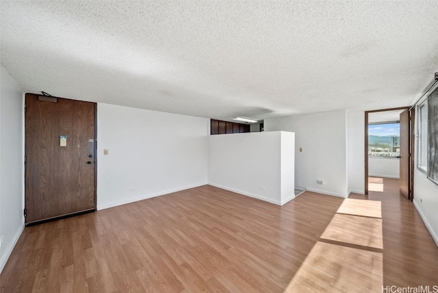 empty room with light hardwood / wood-style floors and a textured ceiling