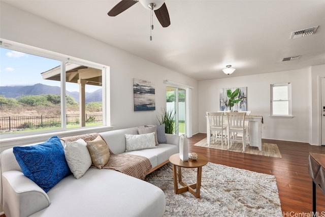 living room with a mountain view, dark hardwood / wood-style flooring, and ceiling fan