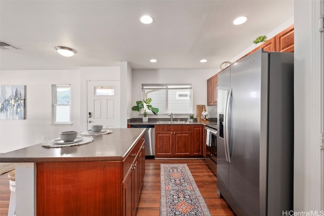 kitchen with appliances with stainless steel finishes, dark hardwood / wood-style flooring, a kitchen island, and sink