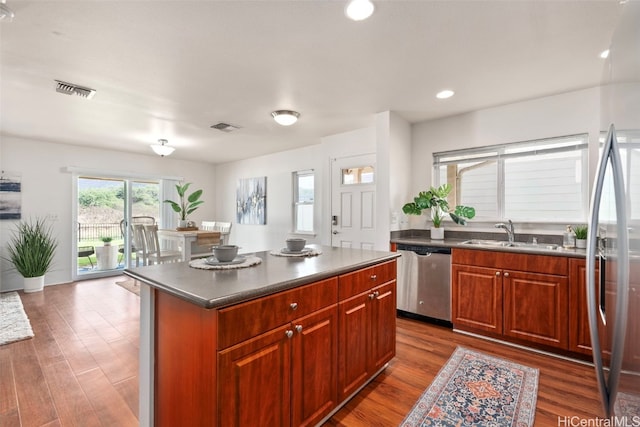 kitchen with stainless steel dishwasher, a kitchen island, sink, and dark wood-type flooring