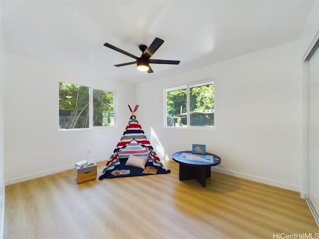 playroom with ceiling fan and light hardwood / wood-style flooring