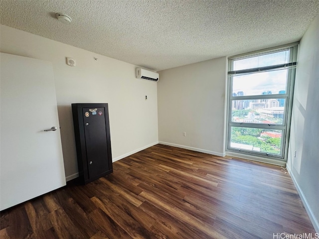 spare room featuring a textured ceiling, dark hardwood / wood-style flooring, a healthy amount of sunlight, and a wall mounted air conditioner