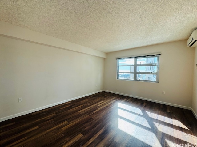 spare room featuring a textured ceiling, dark hardwood / wood-style flooring, and a wall unit AC