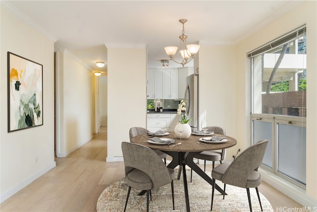 dining area with ornamental molding, light wood-type flooring, and a notable chandelier