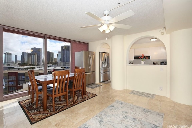 dining room featuring ceiling fan, light tile patterned flooring, a textured ceiling, and a wall of windows